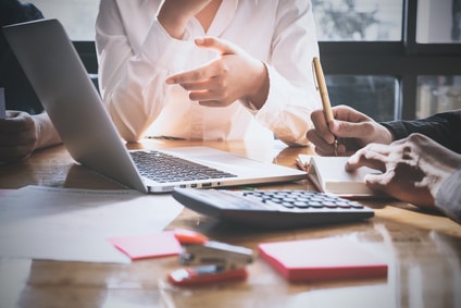 Réunion de travail autour d'un ordinateur et d'une calculatrice